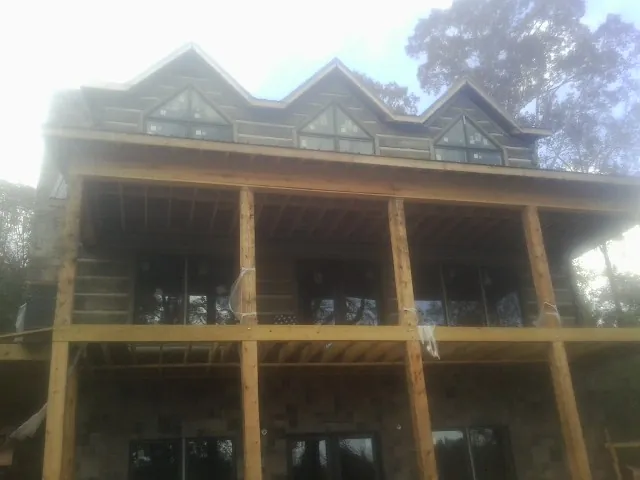 Dormers and porch framing on a large log home under construction — Roof Coating work by our crew in Avery