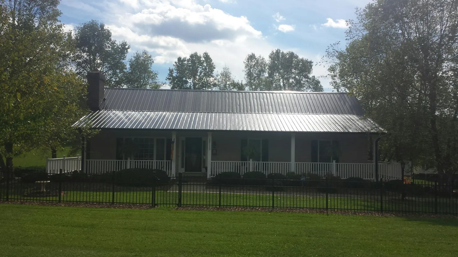 Gray metal roof on a brick ranch with a full width front porch — Gutter Guard Installation work by our crew in Avery