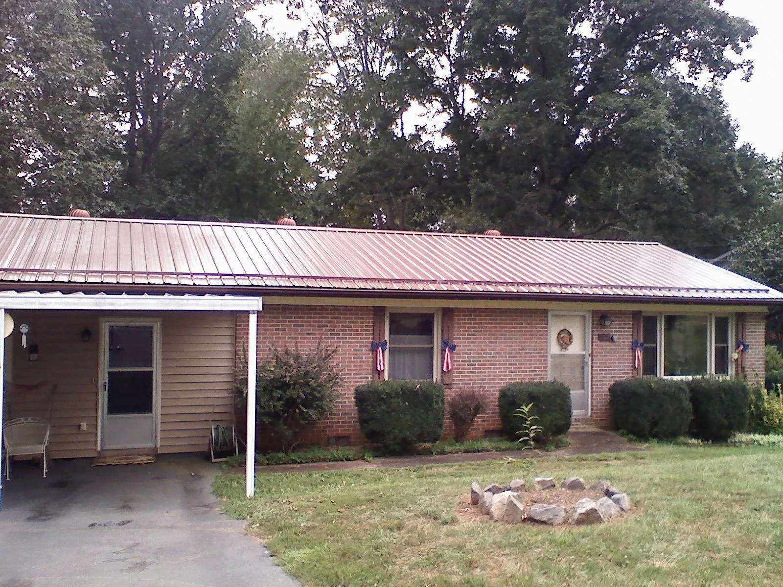 Bronze metal roof and carport on a brick ranch home — Roof Repair work by our crew in Avery