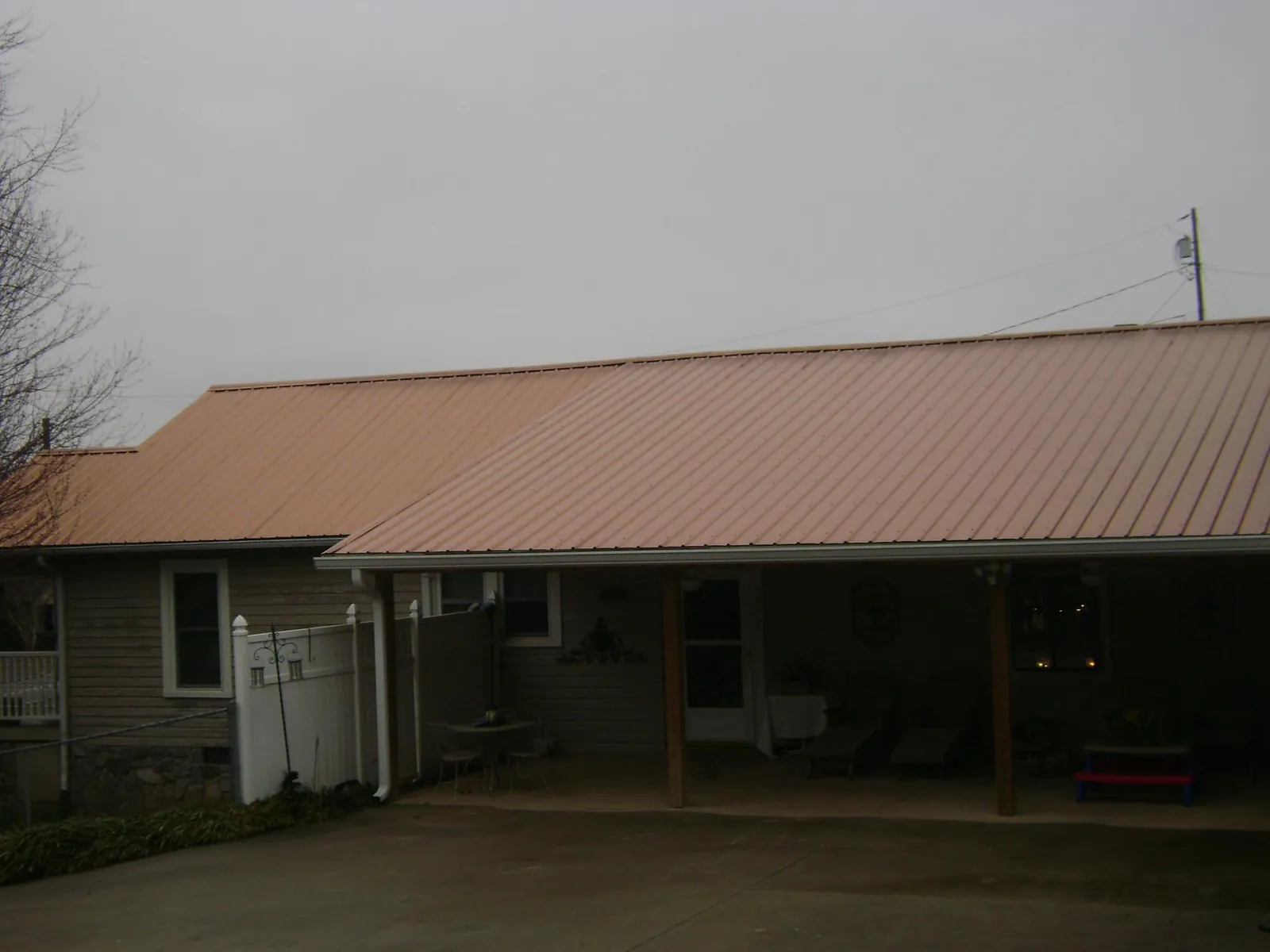 Copper toned metal roof over a wide covered patio in Avery